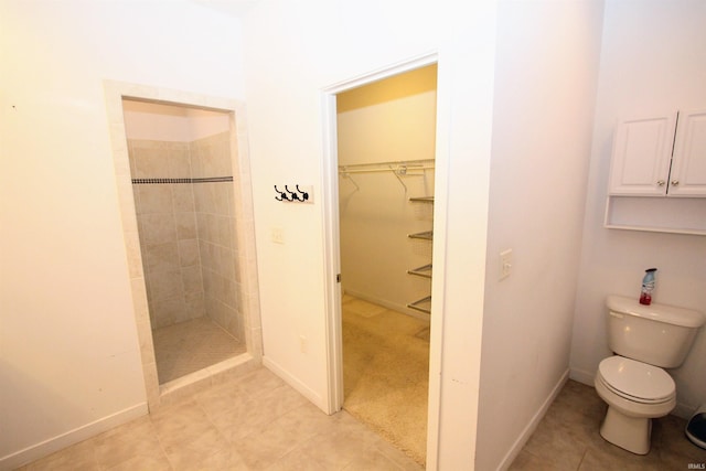 bathroom with a tile shower, tile patterned floors, and toilet