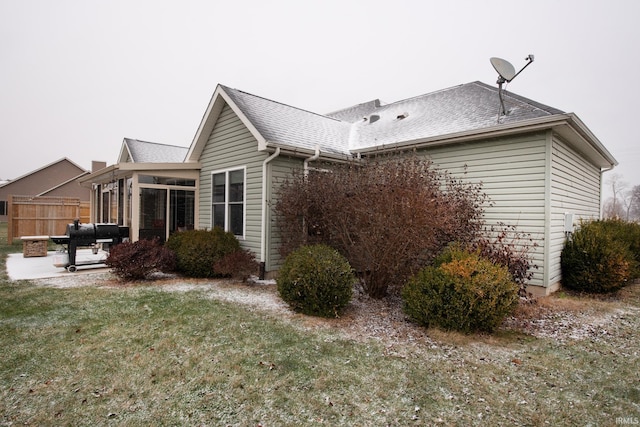 view of property exterior featuring a sunroom, a yard, and a patio area