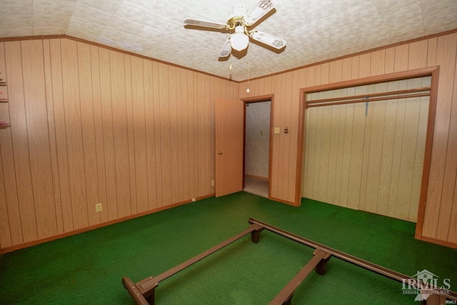 game room with carpet flooring, ceiling fan, wood walls, and vaulted ceiling