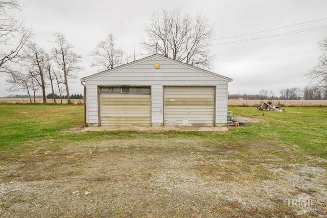 garage with a rural view and a yard