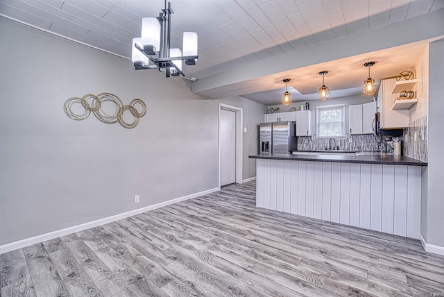 kitchen featuring sink, light hardwood / wood-style flooring, stainless steel fridge, decorative light fixtures, and white cabinets