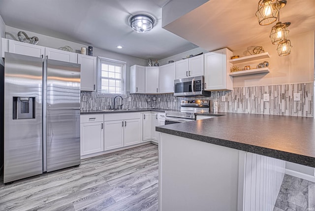 kitchen with kitchen peninsula, appliances with stainless steel finishes, white cabinets, and sink