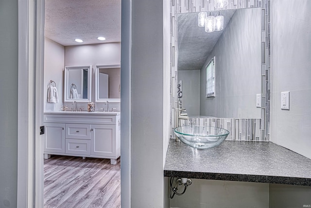 bathroom with hardwood / wood-style flooring, vanity, and a textured ceiling