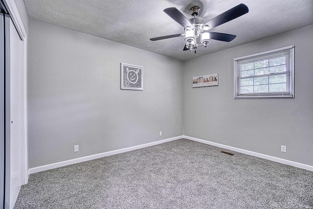 carpeted spare room featuring ceiling fan and a textured ceiling