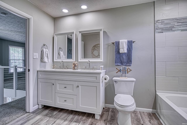 bathroom featuring hardwood / wood-style floors, vanity, a textured ceiling, and toilet