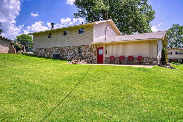 rear view of house featuring central AC and a lawn