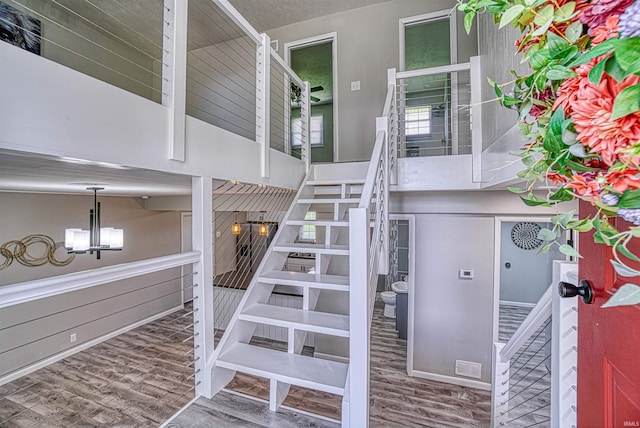 stairway featuring wood-type flooring and an inviting chandelier