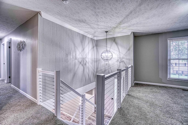 hallway featuring ornamental molding, carpet floors, a textured ceiling, and a chandelier