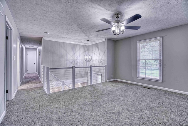 carpeted spare room with ceiling fan with notable chandelier and a textured ceiling