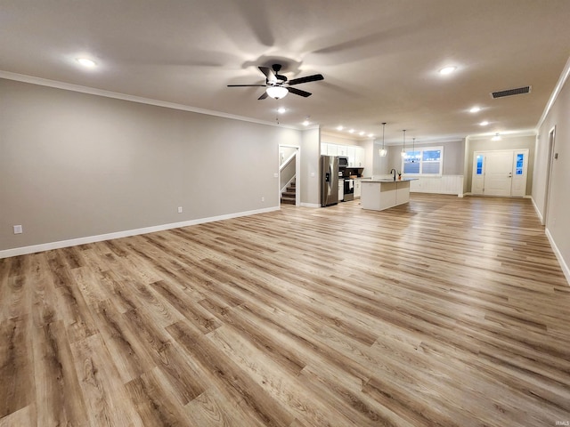 unfurnished living room featuring light hardwood / wood-style floors, ceiling fan, ornamental molding, and sink