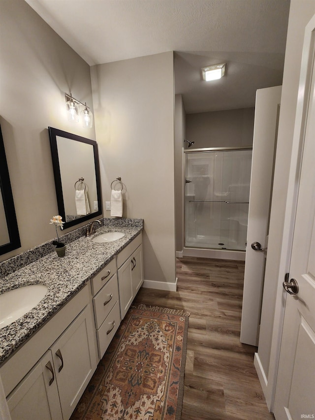 bathroom featuring hardwood / wood-style floors, vanity, a shower with door, and a textured ceiling