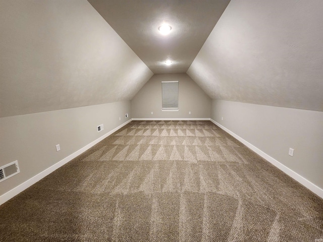 additional living space featuring light carpet and vaulted ceiling