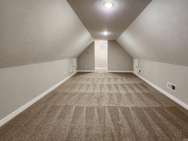 additional living space featuring light colored carpet and vaulted ceiling