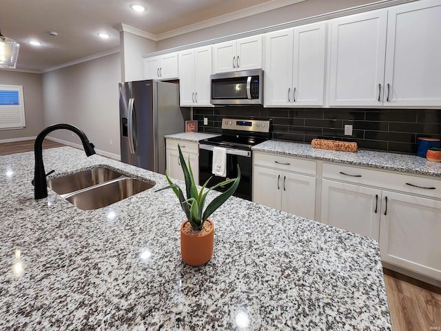 kitchen featuring white cabinets, sink, hardwood / wood-style flooring, decorative backsplash, and appliances with stainless steel finishes