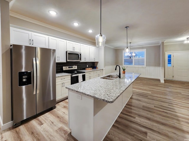 kitchen featuring light wood-type flooring, stainless steel appliances, a kitchen island with sink, sink, and white cabinetry