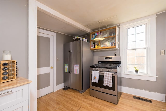 kitchen with pendant lighting, light wood-type flooring, white cabinetry, and appliances with stainless steel finishes