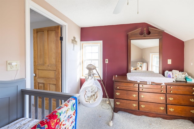 bedroom featuring carpet, ceiling fan, lofted ceiling, and a nursery area