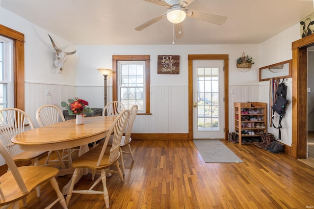 dining space with hardwood / wood-style flooring, plenty of natural light, ceiling fan, and wood walls