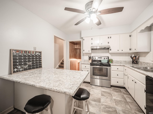 kitchen with kitchen peninsula, decorative backsplash, stainless steel range with electric stovetop, white cabinetry, and a breakfast bar area