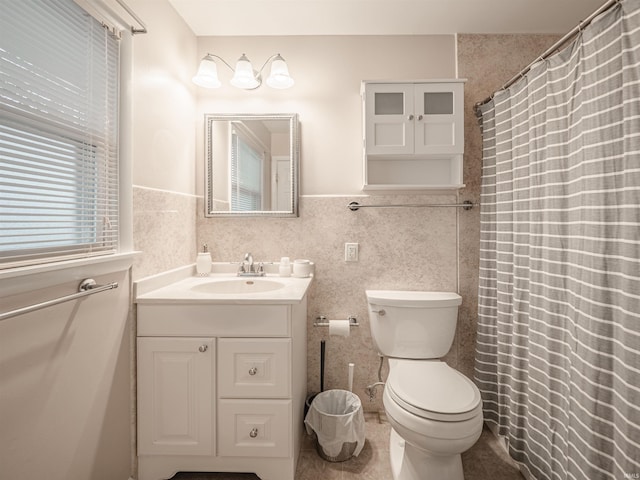 bathroom featuring vanity, toilet, and tile walls