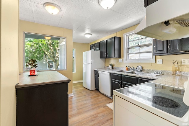 kitchen with light stone countertops, sink, island exhaust hood, white appliances, and light wood-type flooring