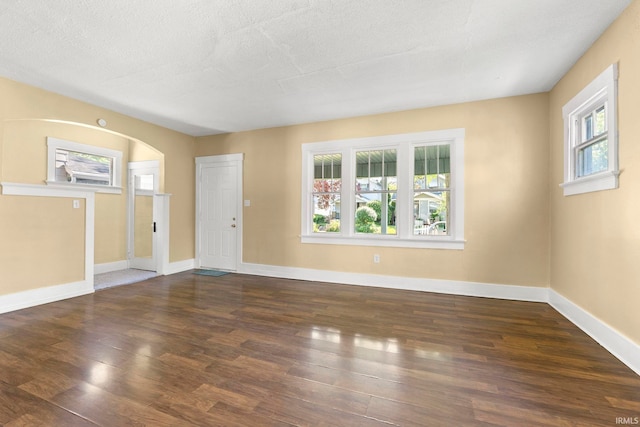 empty room featuring a textured ceiling and dark hardwood / wood-style floors