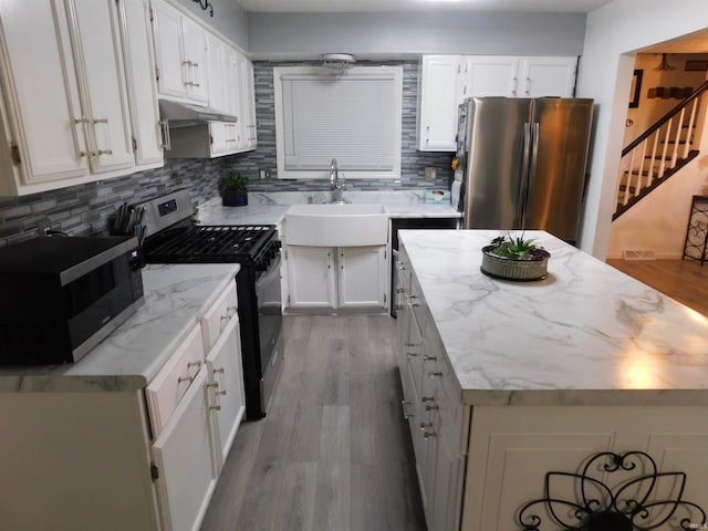 kitchen with light hardwood / wood-style floors, white cabinetry, appliances with stainless steel finishes, and tasteful backsplash