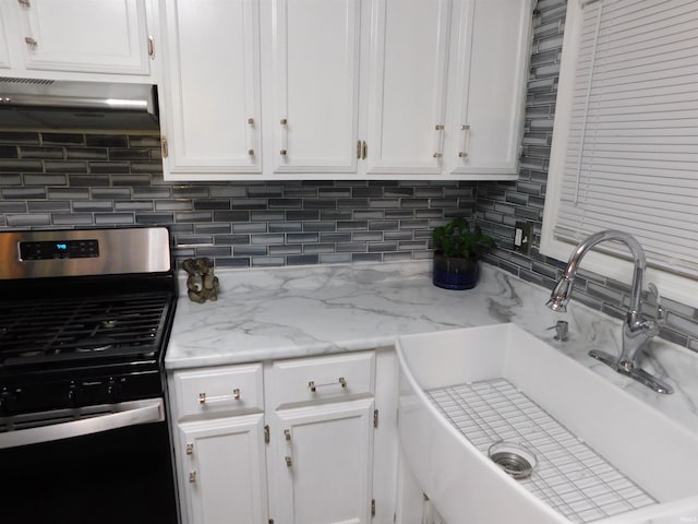 kitchen with decorative backsplash, stainless steel range, sink, white cabinetry, and range hood