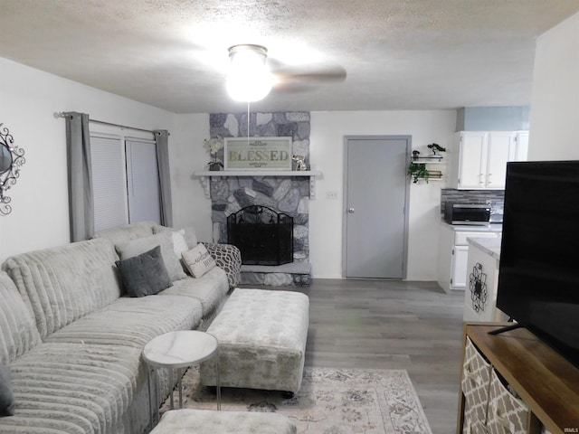 living room with a fireplace, light hardwood / wood-style flooring, and a textured ceiling