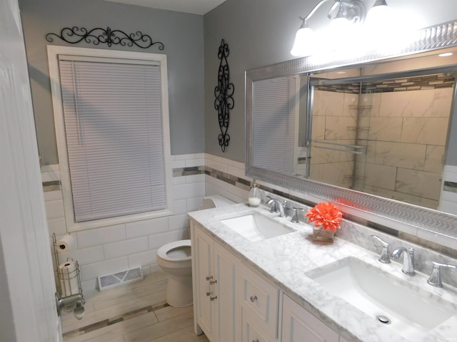 bathroom with vanity, toilet, and tile walls