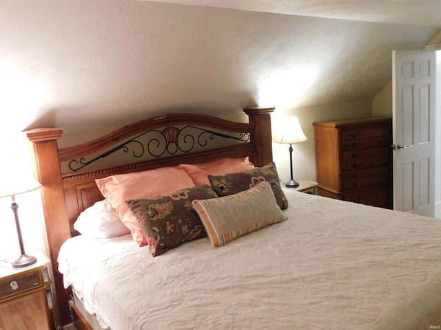 bedroom featuring a textured ceiling and vaulted ceiling