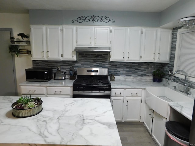 kitchen featuring light stone countertops, stainless steel appliances, white cabinets, and sink