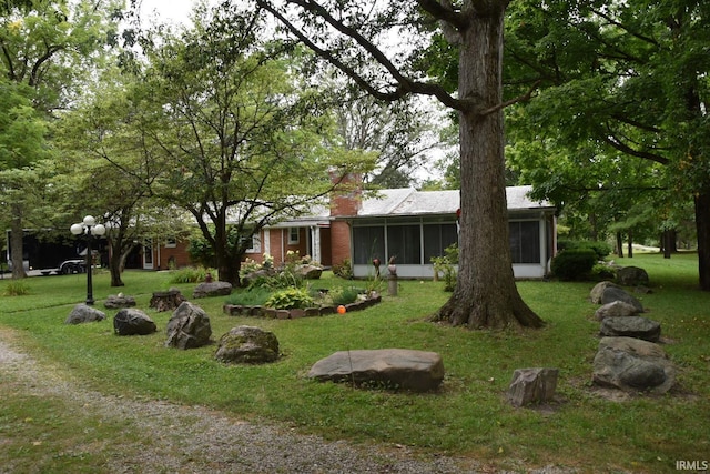 view of front of property featuring a sunroom and a front lawn