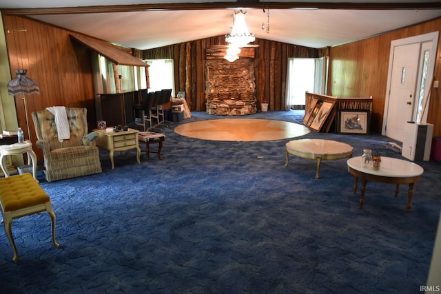 living area featuring carpet flooring, wooden walls, vaulted ceiling, and a healthy amount of sunlight