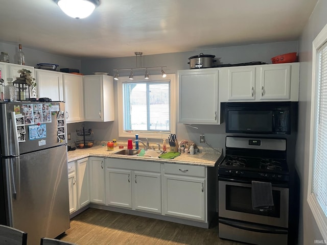 kitchen with light wood-type flooring, stainless steel appliances, sink, decorative light fixtures, and white cabinetry