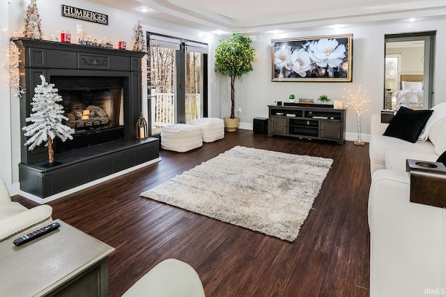 living room with a tiled fireplace and dark hardwood / wood-style flooring