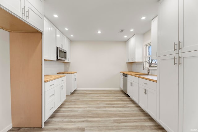 kitchen with butcher block counters, white cabinetry, and stainless steel appliances