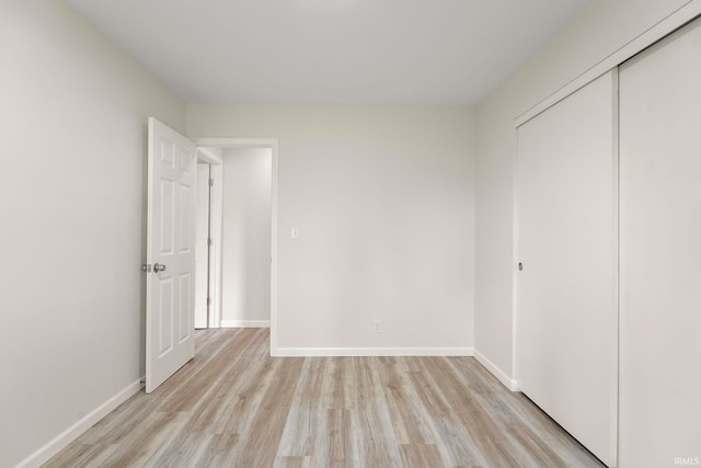 unfurnished bedroom with light wood-type flooring and a closet