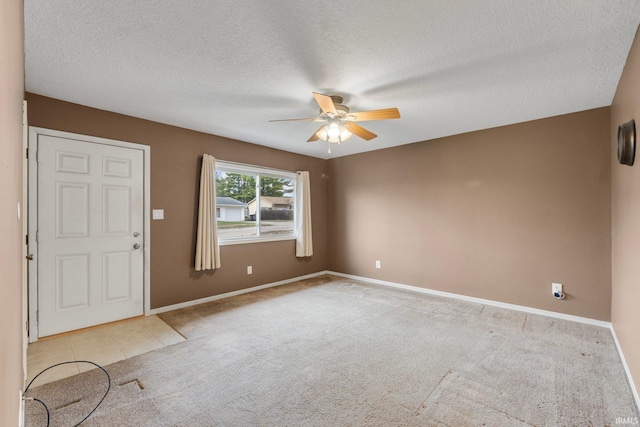 spare room with a textured ceiling, light colored carpet, and ceiling fan