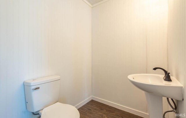 bathroom featuring hardwood / wood-style floors, toilet, wood walls, and sink