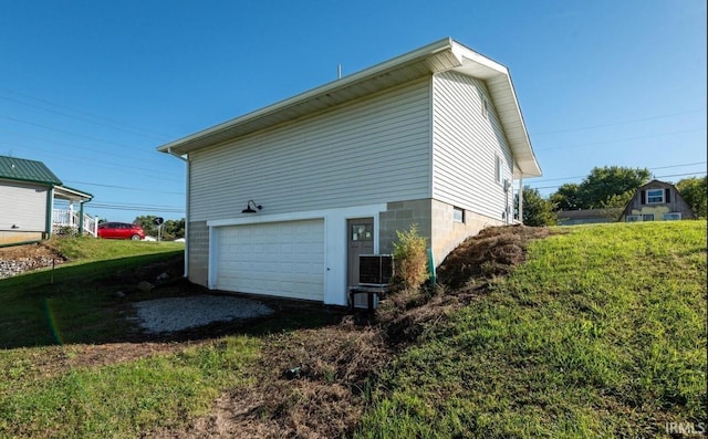 view of side of property with a garage, a yard, and central AC