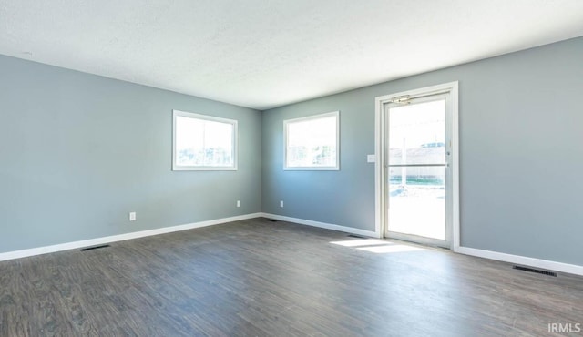 unfurnished room with a textured ceiling and dark hardwood / wood-style floors