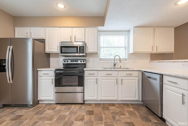 kitchen with sink, white cabinets, a textured ceiling, and appliances with stainless steel finishes