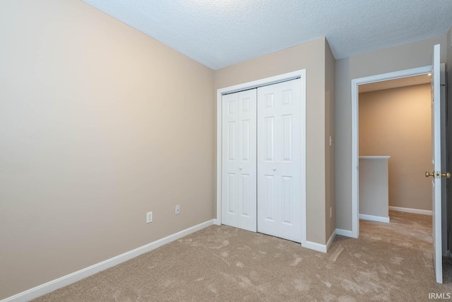 unfurnished bedroom with light carpet, a closet, and a textured ceiling