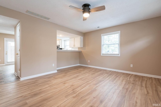 unfurnished living room featuring ceiling fan, light hardwood / wood-style floors, and a textured ceiling