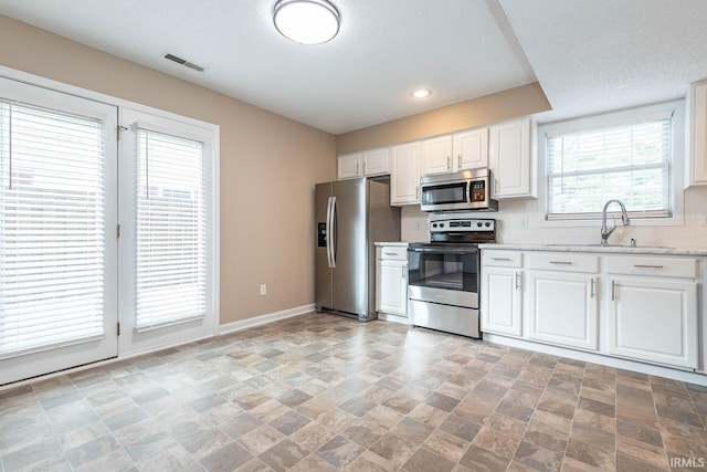 kitchen with sink, stainless steel appliances, tasteful backsplash, a textured ceiling, and white cabinets