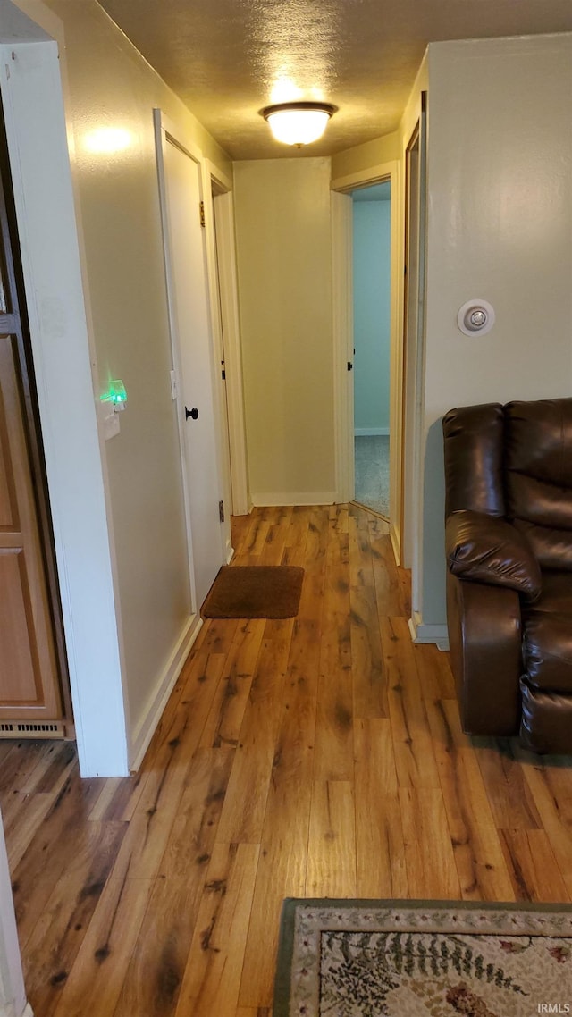 hallway featuring light hardwood / wood-style floors and a textured ceiling