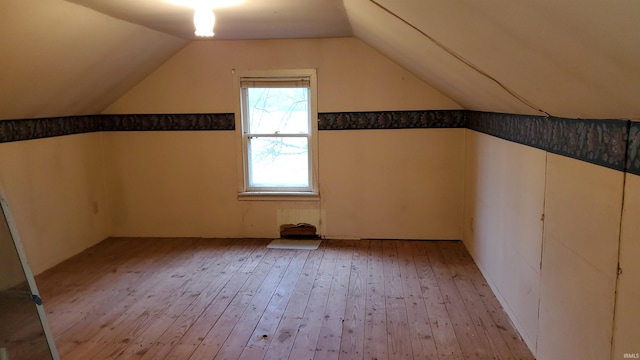 additional living space with light wood-type flooring and vaulted ceiling