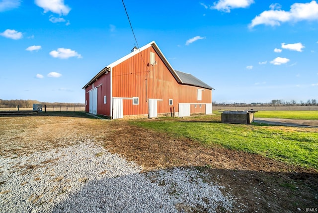 view of side of home with a yard, an outbuilding, and a rural view