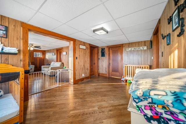 bedroom featuring hardwood / wood-style flooring, a drop ceiling, and wood walls